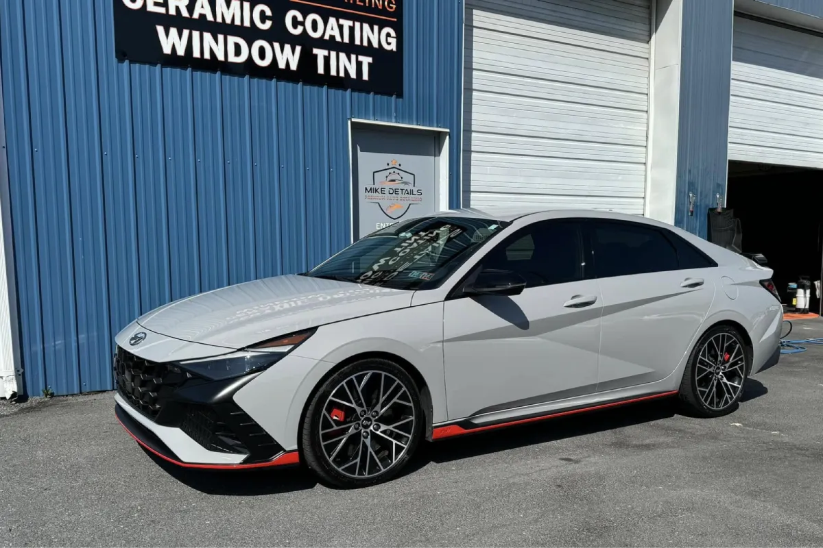 Full side view of a car parked outside a shop with a blue wall.