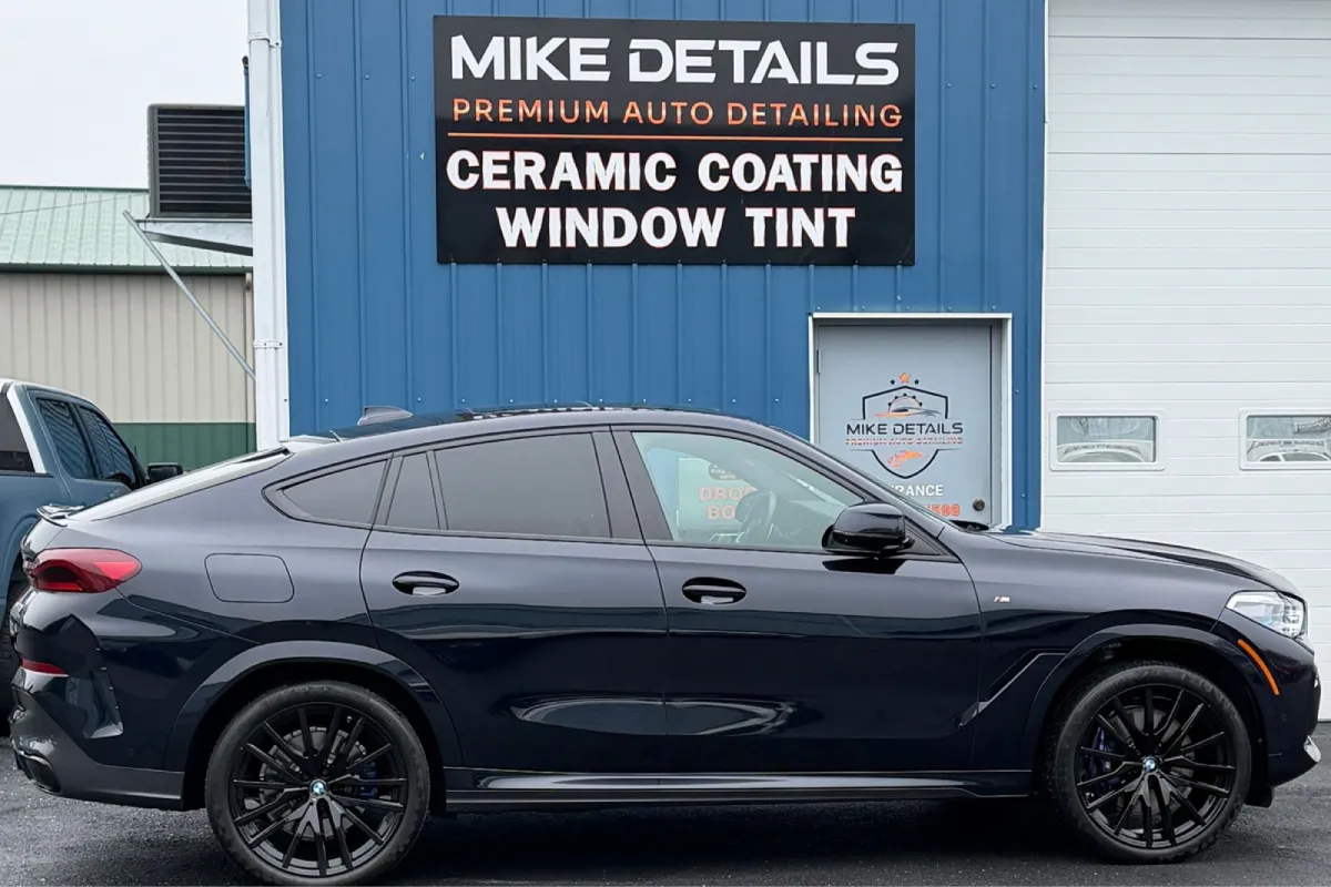 Black BMW X6 SUV parked outside detailing shop with polished finish