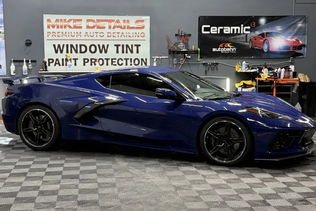 Blue performance car fully protected with paint protection film in a detailing shop, featuring a high-gloss finish.