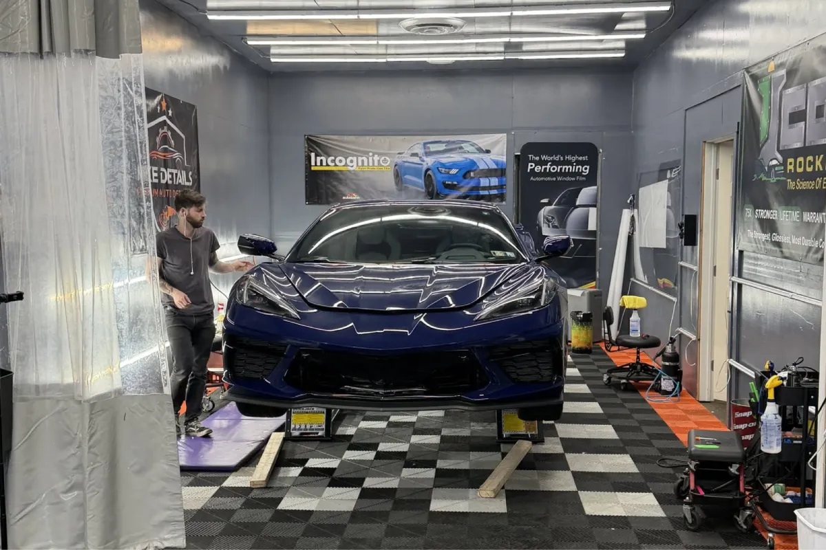 Paint protection film being applied to a sports car during installation, showing clear protective wrap over the front end.
