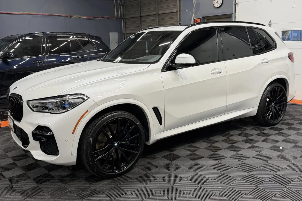 White BMW X5 with dark window tint in detailing shop.