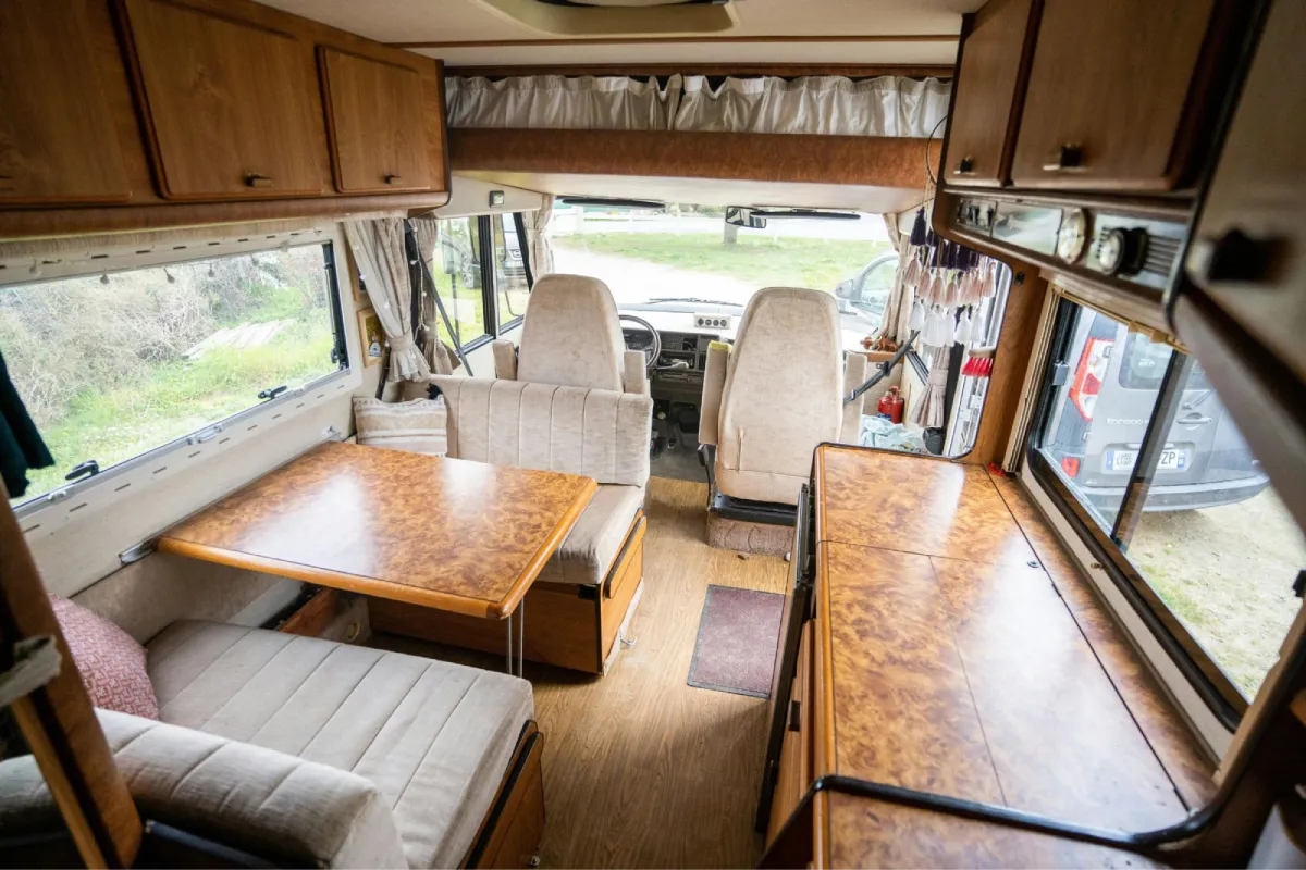 Clean RV interior with detailed seating, cabinets, and dining area.